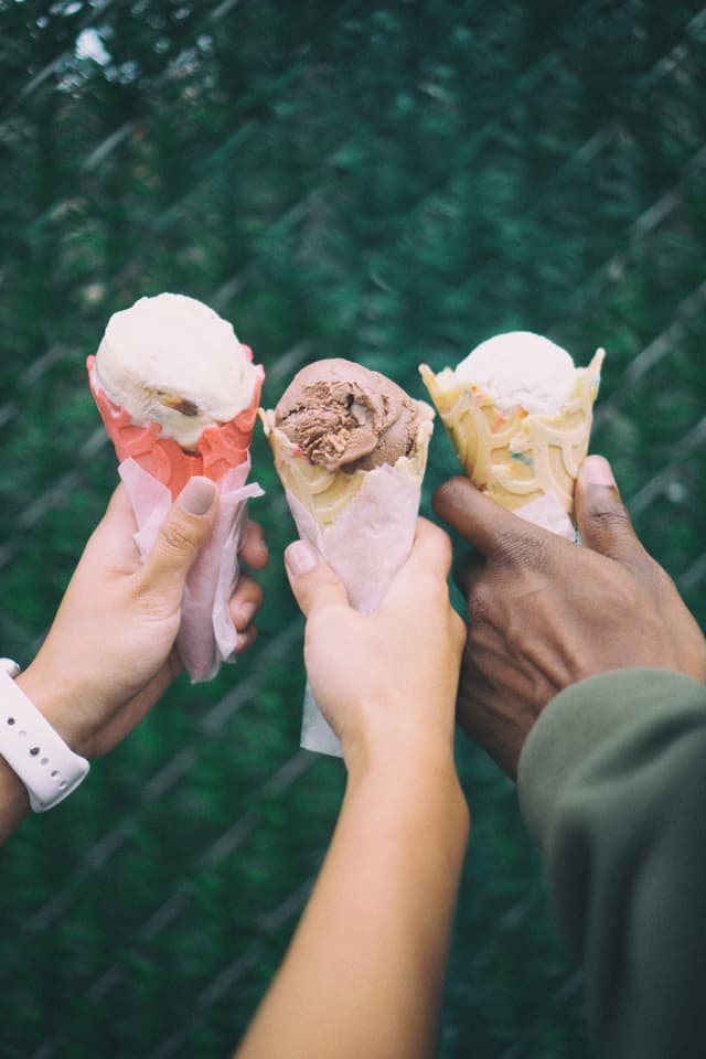 three hands holding ice cream cones